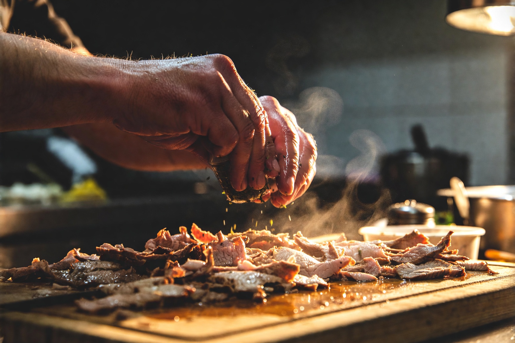 Hände würzen frisch geschnittenes Dönerfleisch